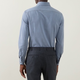 Model wearing Corneliani Herringbone Tonal Striped Shirt in mid blue, rear view, styled with dark charcoal tailored trousers.