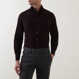 Model wearing dark burgundy slim-fit long-sleeve shirt with spread collar, styled with grey trousers