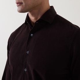 Model wearing dark burgundy button-up shirt with spread collar and navy buttons, close-up detail shot