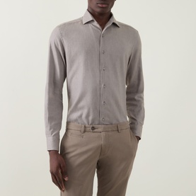 Model wearing a grey long sleeve button-up shirt with spread collar, styled with taupe tailored trousers