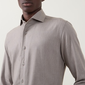 Model wearing a long-sleeve taupe button-up shirt with a spread collar, shown in a close-up crop from chest to shoulder