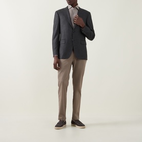 Model wearing dark grey blazer with light shirt and taupe chinos, styled with dark suede loafers
