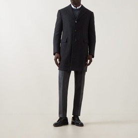 Model wearing dark navy wool overcoat with stand collar and button front, styled with grey trousers and black leather shoes