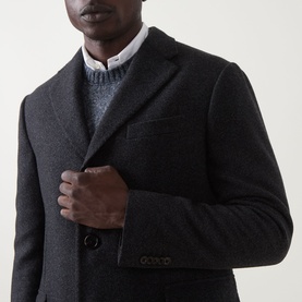 Model wearing dark charcoal wool blazer, styled with grey knit sweater and white shirt collar visible beneath