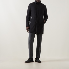 Model wearing Corneliani Technical Padded Coat in black with high neckline and zip pockets, styled with grey trousers and black leather shoes.