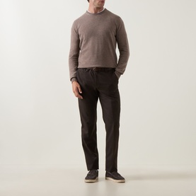 Model wearing Corneliani Logo Knitted Sweater in taupe, crew neck, long sleeves, ribbed trims. Styled with dark trousers and grey shoes.