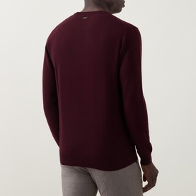 Model wearing Corneliani burgundy wool-cashmere crew neck jumper, back view, styled with light grey trousers.