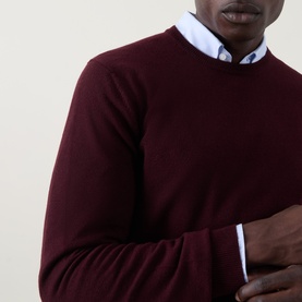 Model wearing Corneliani burgundy wool-cashmere crew neck sweater, styled over a light blue collared shirt.