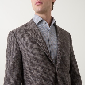 Model wearing Corneliani brown houndstooth wool blazer jacket, styled with a blue checked shirt, close-up chest shot.