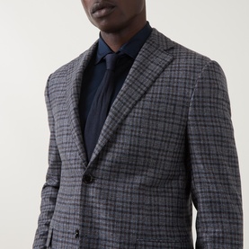Model wearing Corneliani multi check wool jacket in grey and navy, styled with a navy shirt and tie, close-up shot