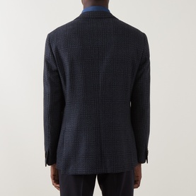 Model wearing Corneliani navy check wool jacket, rear view, with double-button cuffs and centre vent visible