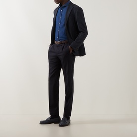 Model wearing Corneliani navy virgin wool jacket, styled with blue shirt, dark trousers, and brown leather belt.