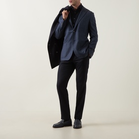 Model wearing Corneliani mid blue virgin wool jacket, styled with black shirt and black trousers, holding lapel open