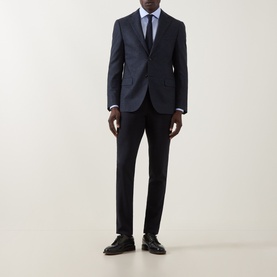 Model wearing Corneliani dark blue wool jacket, styled with matching trousers, light blue shirt, tie, and black leather shoes.