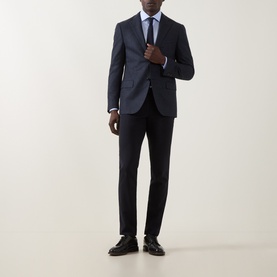 Model wearing Corneliani dark blue wool jacket, styled with matching trousers, light blue shirt and navy tie, black loafers.