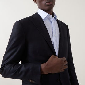 Model wearing Corneliani navy wool-cashmere jacket, single-breasted with notch lapels, styled with white dress shirt and pale blue tie.