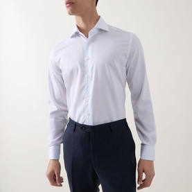 Model wearing Corneliani Poplin Polkadot Shirt in white, long sleeves, pointed collar, structured cuffs, styled with navy trousers.