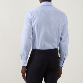 Model wearing Corneliani blue cotton formal shirt, single cuff regular fit, shown from the back, paired with dark navy trousers.
