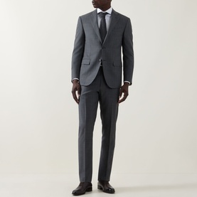 Model wearing Corneliani grey wool suit with notch lapels, styled with white shirt, navy tie and black dress shoes.