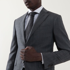 Model wearing Corneliani grey check wool suit jacket, styled with white shirt and dark patterned tie