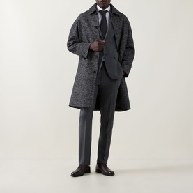 Model wearing Corneliani grey wool suit with white shirt and tie, styled with a dark herringbone overcoat and black dress shoes