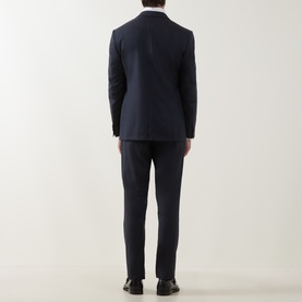 Model wearing Corneliani Tonal Herringbone Two-Piece Suit in dark blue, rear view, with black dress shoes.