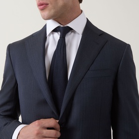 Model wearing Corneliani Tonal Herringbone Two-Piece Suit in dark blue, styled with a white shirt and navy tie.