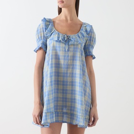 Model wearing Damson Madder Harlow Check Mini Dress in blue check with ruffle neckline, short puff sleeves and shirred cuffs