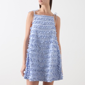 Model wearing Damson Madder blue mini dress with tiered ruffle texture, tie shoulder straps and A-line silhouette.