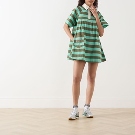 Model wearing Damson Madder Maggie Polo Dress in green multi stripe, mini length with polo collar, styled with white trainers