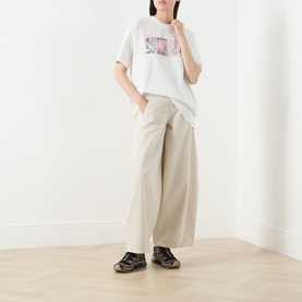 Model wearing Damson Madder Erika Barrel Leg Jeans in stone, wide barrel-leg cut, styled with white graphic tee and dark chunky trainers.
