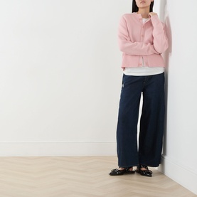 Model wearing Damson Madder Augusta Mid-Rise Straight Leg Jeans in Dark Indigo with wide straight legs, styled with a pink cardigan and black loafers.