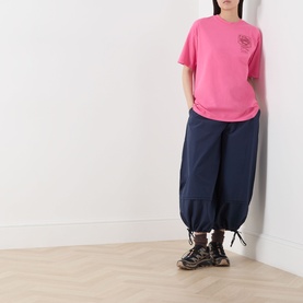Model wearing Damson Madder Gill Of Dreams Graphic T-Shirt in pink with navy cropped balloon trousers and chunky trainers.