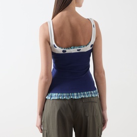 Model wearing Damson Madder navy cotton camisole top with contrast print trim, ruffle hem, and wide straps, styled with khaki trousers.