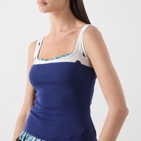 Model wearing Damson Madder navy cotton camisole top with cream scoop neckline trim and thin straps, styled with printed shorts.