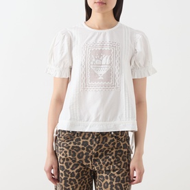 Model wearing Damson Madder white cotton top with puff sleeves and embroidered chest detail, styled with leopard-print trousers.