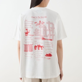 Model wearing Damson Madder off white cotton T-shirt, back view showing red crossword and slow life graphic print.