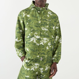 Model wearing BAPE Pixelated Camo Print Logo Windbreaker in green, styled with matching camo joggers. Zip-up, high neck, dropped shoulders.