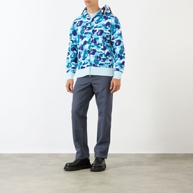 Model wearing blue camouflage zip-up hoodie with hood, styled with grey trousers and black shoes
