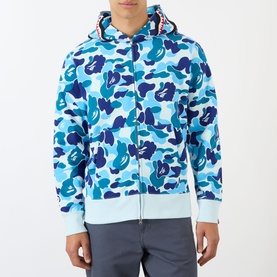 Model wearing blue camouflage zip-up hoodie with contrast striped hood lining, paired with light blue shorts.