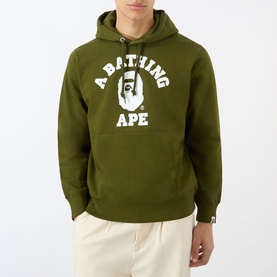 Model wearing A Bathing Ape olive green pullover hoodie with white collegiate logo graphic, styled with cream trousers