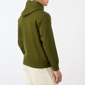 Model wearing olive green pullover hoodie with rear view, styled with cream trousers