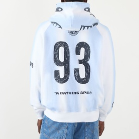 Model wearing BAPE Hand Drawn Football Zip Hoodie in white, back view showing number 93 graphic and shark hood detail, styled with blue jeans.