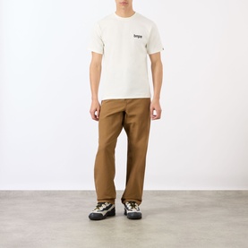 Model wearing BAPE A Bathing Ape Logo T-Shirt in ivory, styled with tan wide-leg trousers and chunky hiking trainers.