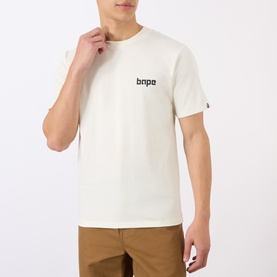 Model wearing BAPE A Bathing Ape Logo T-Shirt in ivory, crew neck, short sleeves, small logo graphic on chest, styled with tan trousers.
