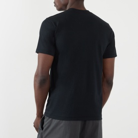 Model wearing BAPE ABC Camouflage College Logo Shirt in black, rear view showing round neck and short sleeves. Styled with grey shorts.