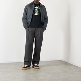 Model wearing BAPE ABC Camouflage College Logo Shirt in black with grey jacket, wide-leg trousers and low-top trainers.