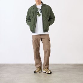Model wearing BAPE Lighter Relaxed Fit T-Shirt in white, styled with olive quilted bomber jacket, tan cargo trousers and chunky trainers.