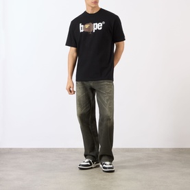 Model wearing BAPE Graffiti Logo Relaxed Fit T-Shirt in black with washed green wide-leg jeans and black trainers.