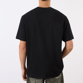 Model wearing BAPE Graffiti Logo Relaxed Fit T-Shirt in black, back view, showing dropped shoulders and relaxed fit, styled with khaki trousers.